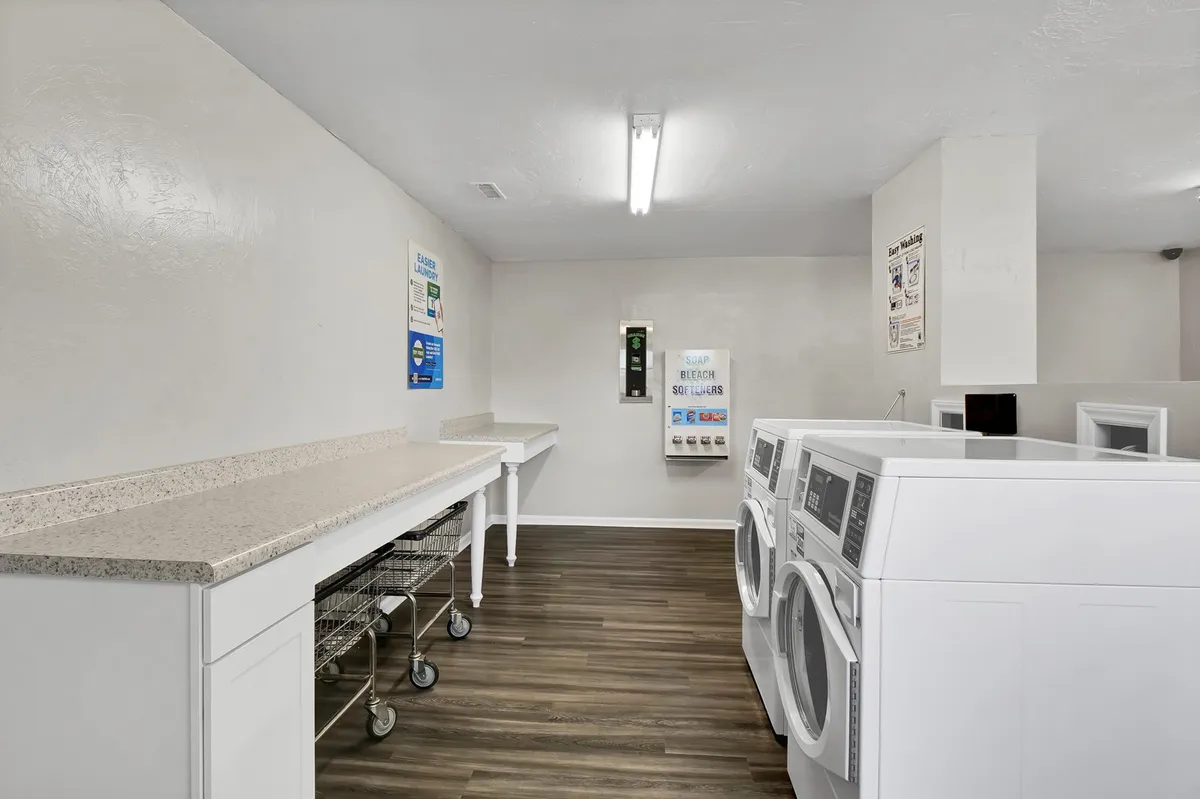 A practical laundry area equipped with washing machines, a folding counter, and laundry baskets, designed for efficient and convenient use by guests.